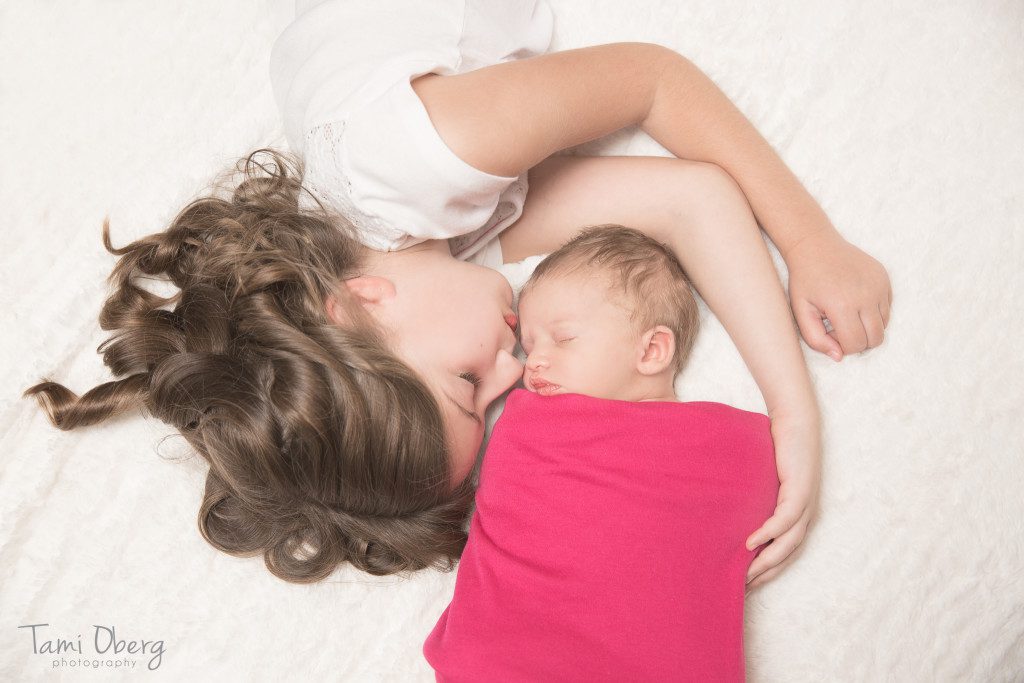 baby sister kissing newborn baby