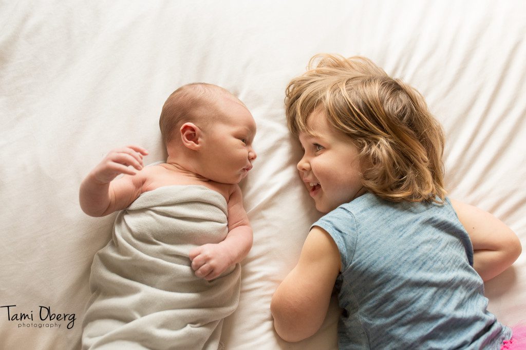 newborn boy looking at big sister