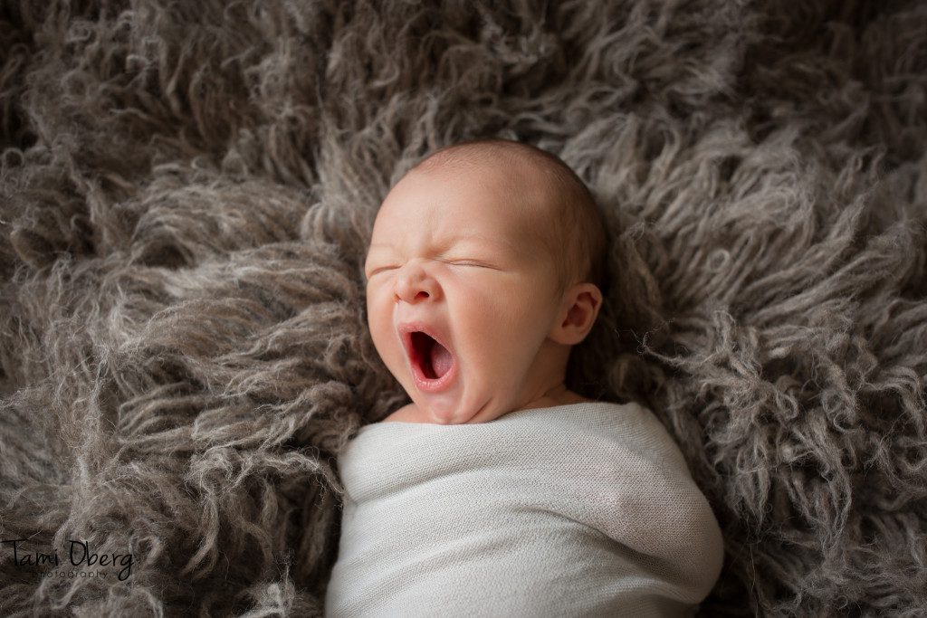 newborn yawning on flokati rug