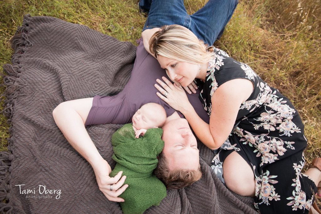 newborn and family lying on blanket