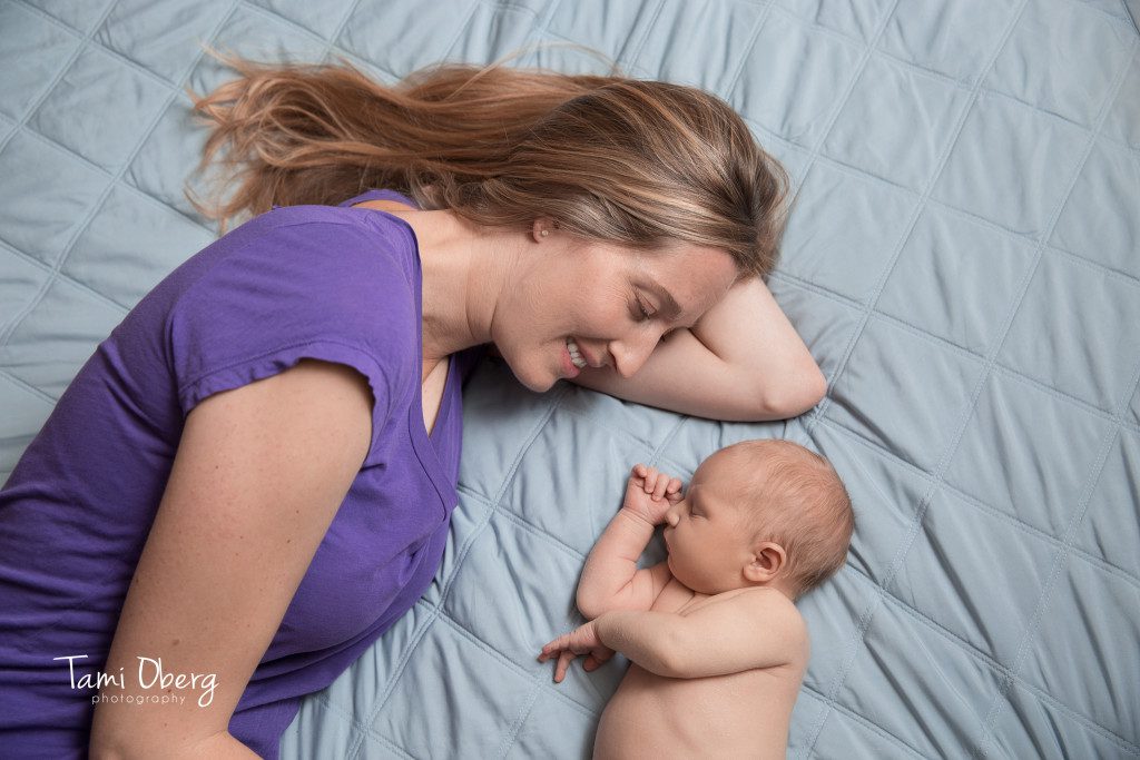 newborn baby boy lying with his mom on a bed