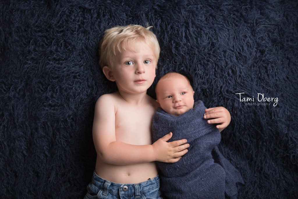 newborn sibling shot on a blue flokati rug