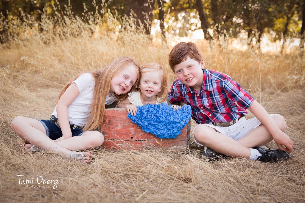 three kids with little sister in a crate