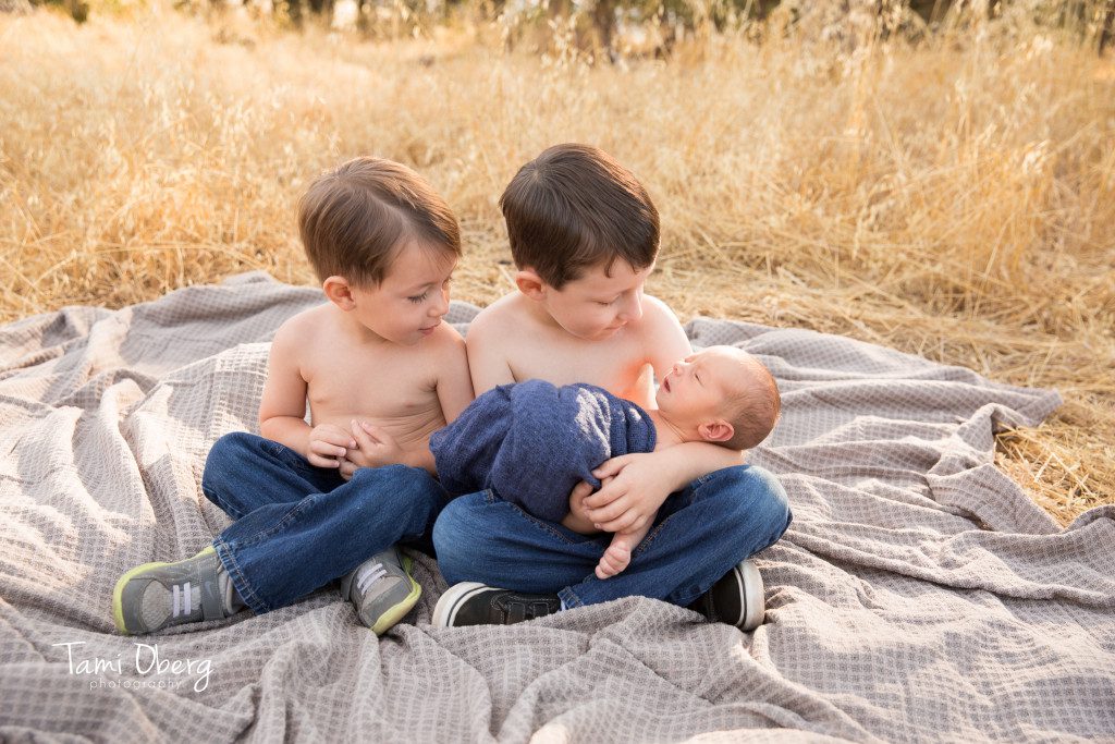toddlers holding newborn baby brother