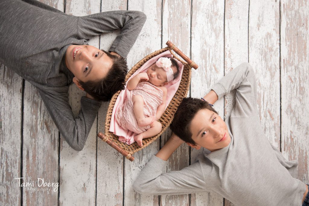 twin boys lying with baby sister