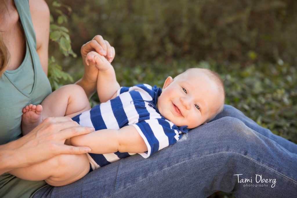 3 month old smiling on his mom's lap
