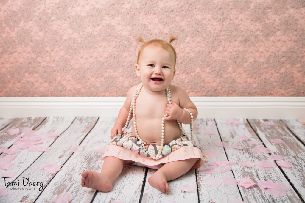 one year old with a long string of pearls